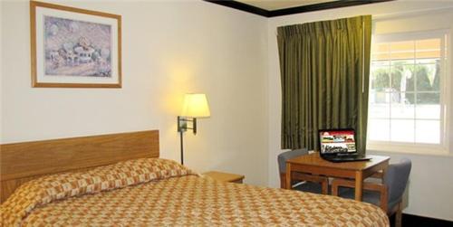 una camera d'albergo con letto e scrivania con computer portatile di Town House Motel a Chico
