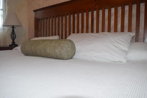 a white bed with a wooden headboard and white pillows at Hotel Casa el Moro in Puerto Morelos