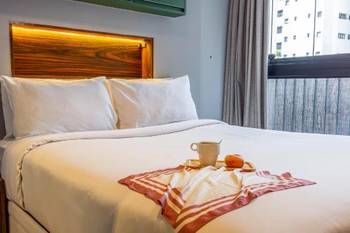 a hotel room with a white bed with a tray on it at Next Home Design by Viva - Apartamentos em prédio próximo ao Parque do Ibirapuera in Sao Paulo