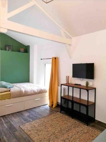 une chambre avec un lit et une télévision à écran plat dans l'établissement L'atelier de Pauline, à Villennes-sur-Seine