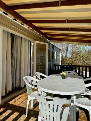 - une table et des chaises blanches sur une terrasse couverte dans l'établissement Mobile-home 3 chambres chaleureux et calme, à Seillac