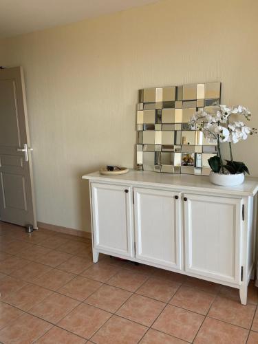un meuble blanc avec un vase de fleurs sur lui dans l'établissement Blue Bay Issambres, aux Issambres