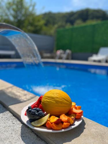 a plate of fruit on a table next to a pool at Rest House in Slavinovići