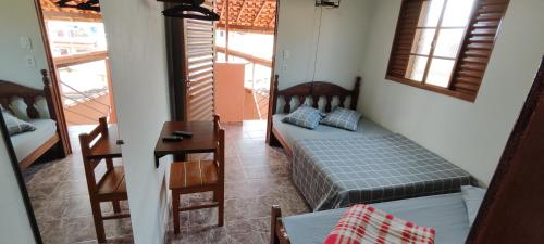 Camera con letto, tavolo e finestre di Pousada Chega Mais a São Thomé das Letras
