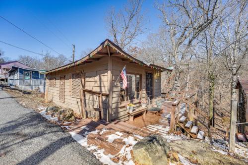 Una pequeña cabaña de madera con una bandera en el porche. en Branson Area Couples Cabin with Wraparound Porch!, en Rockaway Beach