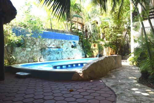 a bath tub in a yard with a stone wall and trees at Hotel Casa el Moro in Puerto Morelos