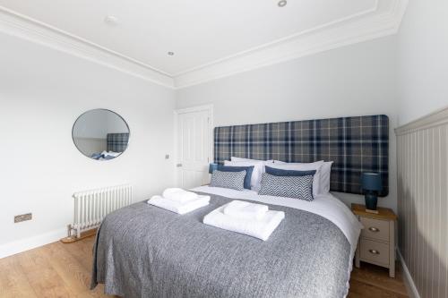 a white bedroom with a large bed with two pillows at Hillside Luxury Apartments in Inverness