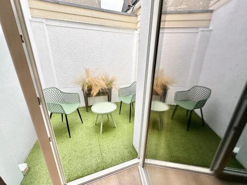 a balcony with tables and chairs in a room at RDC familial à 2 min à pieds de la plage de Berck avec Garage privé in Berck-sur-Mer