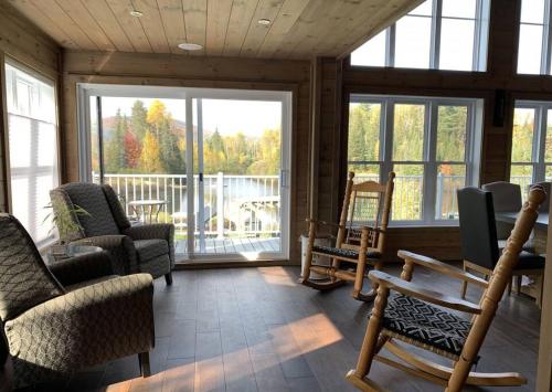 a living room with rocking chairs and a balcony at Formidable Waterfront Cottage - Formidable Chalet sur bord de l'eau in Saint Come