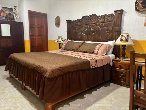 a bedroom with a large bed with a wooden headboard at Casa Palagui Colonial in Valladolid