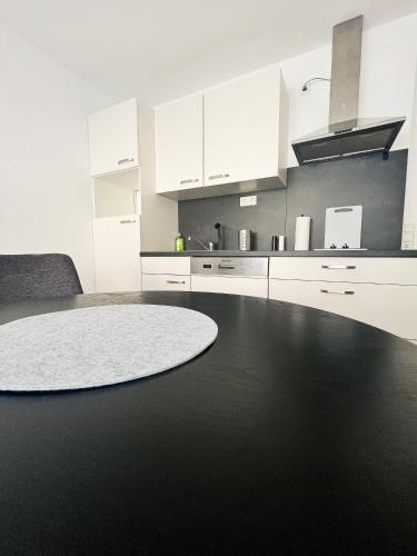 a kitchen with white cabinets and a black floor at Modern Apartment Wissenbach 2 barrierefrei in Eschenburg