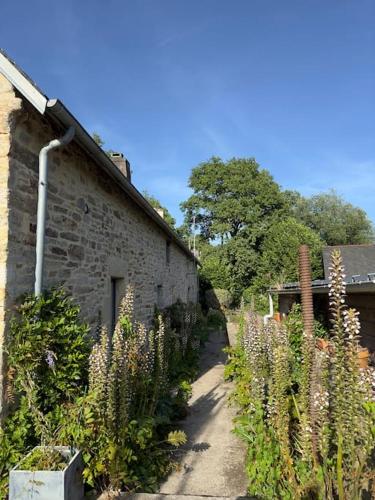 Un bâtiment en pierre avec un bouquet de fleurs à côté dans l'établissement Peaceful Retreat in Traditional Stone House, à Pluvigner