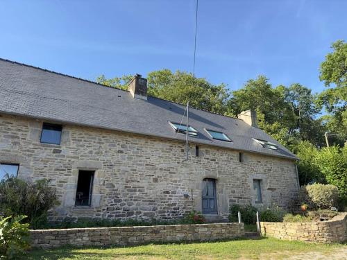 Cette ancienne maison en pierre possède des fenêtres et un toit. dans l'établissement Peaceful Retreat in Traditional Stone House, à Pluvigner