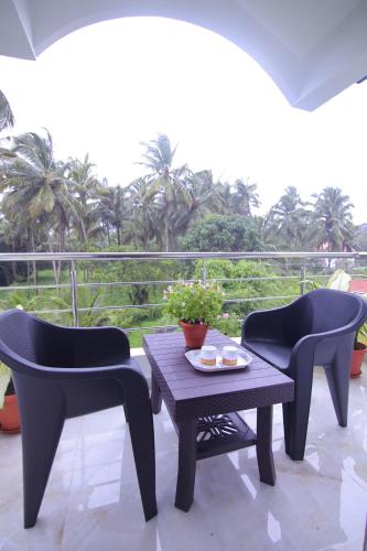 two chairs and a table on a patio with a view at Margaritas Residency in Benaulim