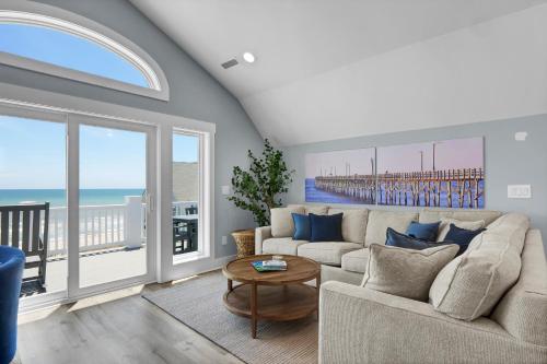 a living room with a couch and a view of the ocean at Grand Topsail Villa by Sea Scape Properties in North Topsail Beach