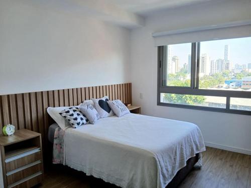 a bedroom with a bed and a large window at Studio Passos do metrô carrão in Sao Paulo