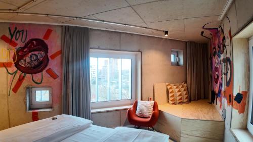 a bedroom with a bed and a window and a chair at Villa Viva - ein Haus das Brunnen baut in Hamburg