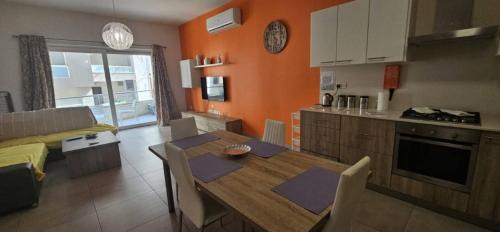 a kitchen and living room with a wooden table and a dining room at Cozy Apartment 2 bdr 2 bth Terrace near Promenade J2 in Il-Gżira