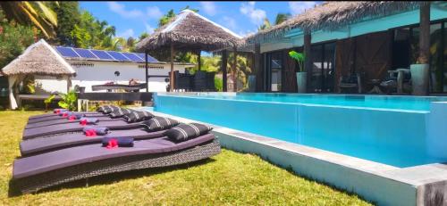 a row of chaise lounges next to a swimming pool at La VILLA BORAHA 300m2 PROPRIÉTÉ ENTIERE en bord de plage PISCINE PRIVEE Cuisine TV Wifi in Sainte Marie