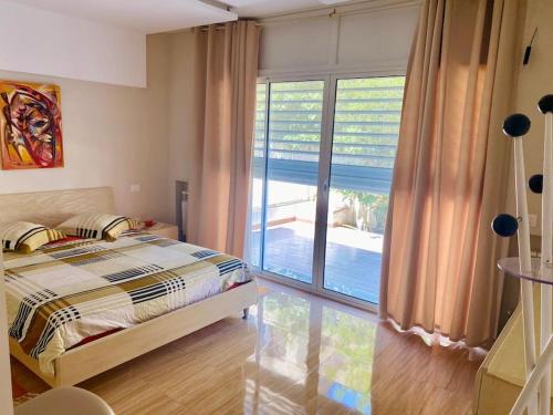 Dar el KoudiaにあるVilla Deluxe, pool, spacious garden, mountain viewのベッドと大きな窓のある寝室