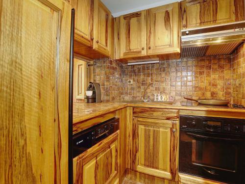 - une cuisine avec des placards en bois et des appareils noirs dans l'établissement Courchevel 1850 - Appart 4 pers avec parking et wifi - skis aux pieds - FR-1-575-216, à Courchevel
