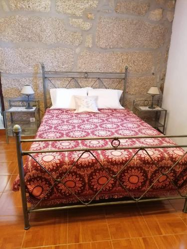 a bed with a red blanket and two pillows at Villa Cantinho dos Avós in Baião