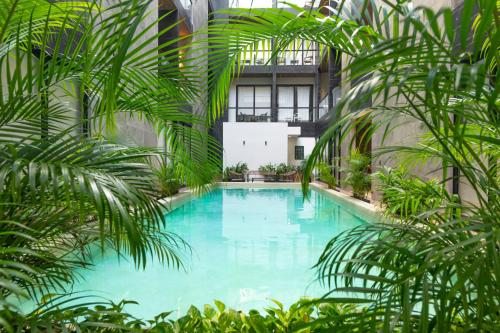 a large pool with palm trees in a building at Musa del Carmen By Boutique Apartments MX in Playa del Carmen