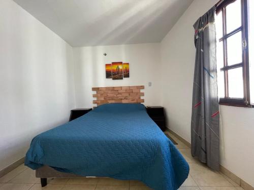 a bedroom with a blue bed and two windows at Monoambiente Tilcara in Tilcara