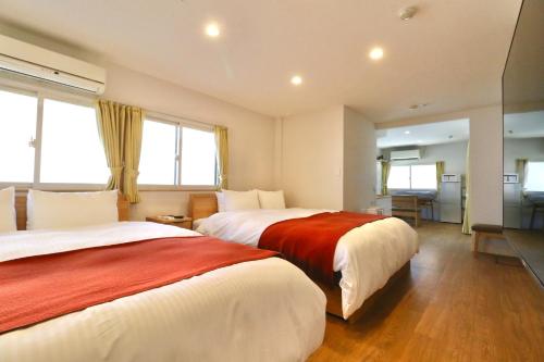 two beds in a hotel room with windows at Corpo Tenma Guesthouse Pegasus - Vacation STAY 55414v in Takayama