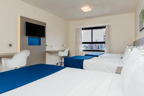 a hotel room with two beds and a tv at Bourbon Hotel Fortaleza in Fortaleza