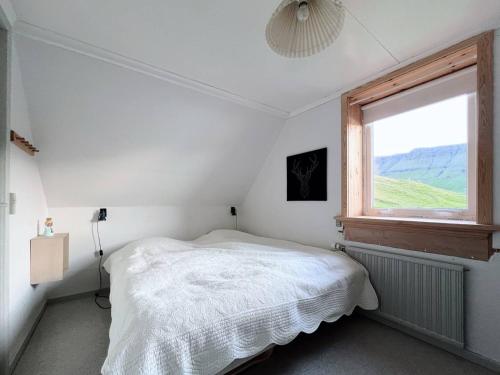 a white bedroom with a bed and a window at Cozy Older House In Brilliant Nature in Hvalba
