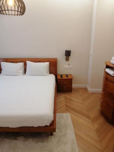 a bedroom with a bed with white sheets and wooden floors at На 2 мин от плажа!Victoria- две спални делукс до Морската градина и центъра in Burgas