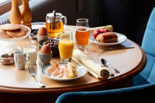 Hotel Restaurant Les Glycines في Vieille-Brioude: طاولة إفطار مع طعام الإفطار وعصير البرتقال