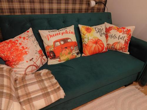 a green couch with pillows on it with pumpkins at Gímes Apartman in Cserszegtomaj