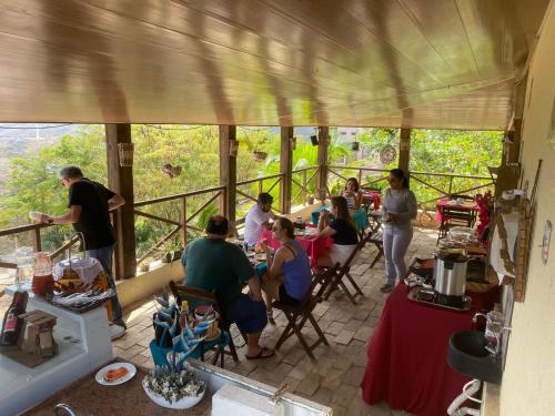 a group of people sitting at tables on a porch at Encanto dos Pássaros in Monte das Gameleiras