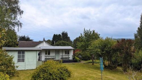 a small white house in a yard at Studio cottage in Tummel Bridge