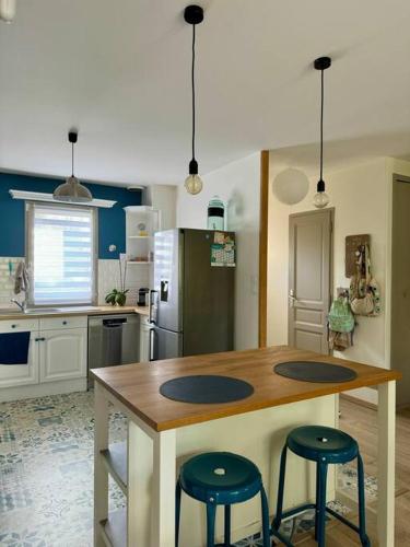 une cuisine avec une table en bois et deux tabourets dans l'établissement Les Acacias - Maison de campagne, à Saint-Sulpice