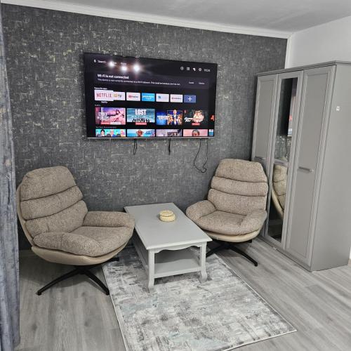 a waiting room with two chairs and a flat screen tv at Garsoniera Delia in Braşov