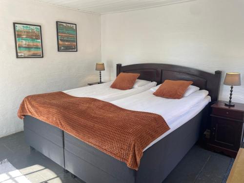 a bedroom with a large bed with white sheets and orange pillows at Husargårdens Bed & Breakfast in Sjöbo