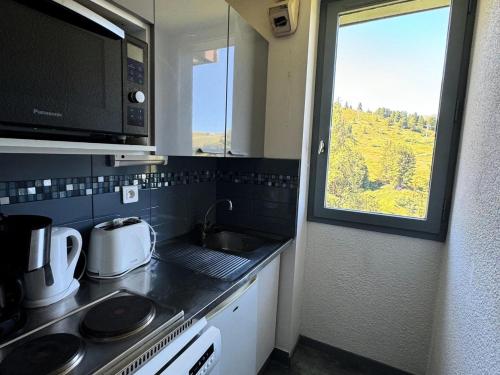 une petite cuisine avec un évier et une fenêtre dans l'établissement Résidence Turquoise - 2 Pièces pour 5 Personnes 89, à Mâcot La Plagne