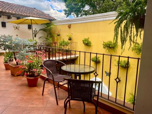 a balcony with a table and chairs and a yellow wall at Hotel la Galería in Antigua Guatemala