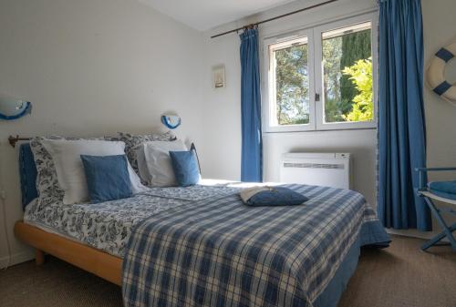 - une chambre avec un lit doté de rideaux bleus et d'une fenêtre dans l'établissement Mas de Charles, à Lorgues