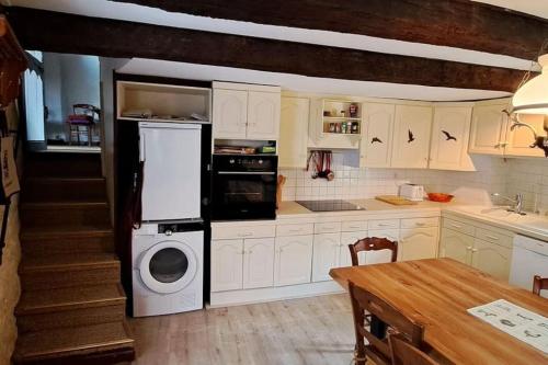 une cuisine avec des armoires blanches et une laveuse et une sécheuse dans l'établissement Havre de paix a Domme, à Domme