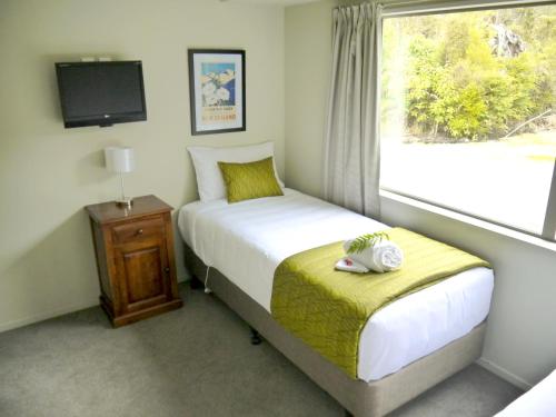 um pequeno quarto com uma cama e uma janela em Franz Josef Treetops em Franz Josef