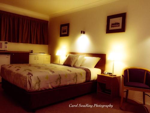 a bedroom with a bed with two lights on it at Ten Dollar Town Motel in Gulgong
