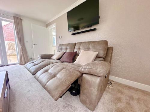 a brown leather couch in a living room with a flat screen tv at A luxury detached 4 bed home in Pontnewydd