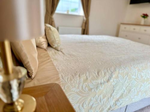 a bedroom with a bed with a lamp on a table at A luxury detached 4 bed home in Pontnewydd
