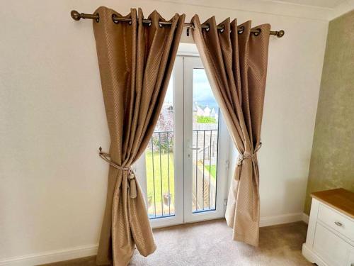 a window with curtains in front of a door at A luxury detached 4 bed home in Pontnewydd