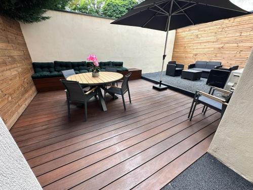 un patio avec une table, des chaises et un parasol dans l'établissement Le Briand Appartement 4étoiles Nancy Thermal Cosy avec Terrasse Wifi, à Laxou
