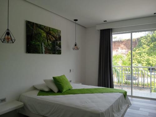 a bedroom with a bed and a large window at Hotel Monte Bello in Doradal